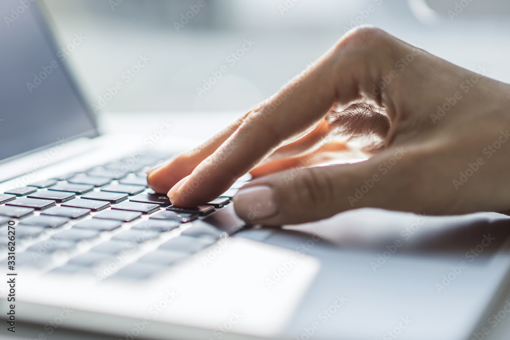 Woman typing on laptop keyboard in sunny office, business and technology concept. Close up Woman typing on laptop keyboard in sunny office, business and technology concept. Close up