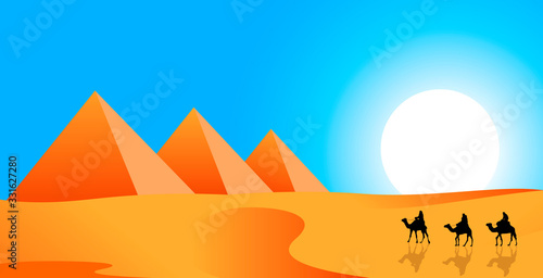 Camel riders on a background of pyramids. Camel caravan follows in the desert. Pyramids  sand desert against the blue sky and sun