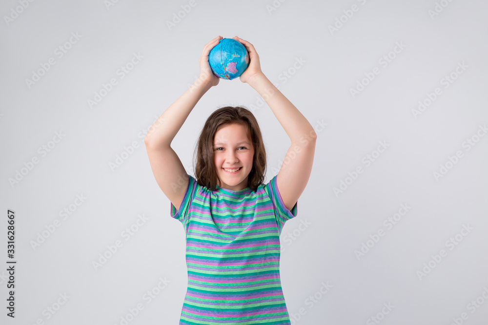 Happy little schoolgirl with globe on her head, standing against white background. Back to school concept. Ideal for banners, registration forms, presentation. Happy little schoolgirl with globe on her head, standing against white background. Back to school concept. Ideal for banners, registration forms, presentation.