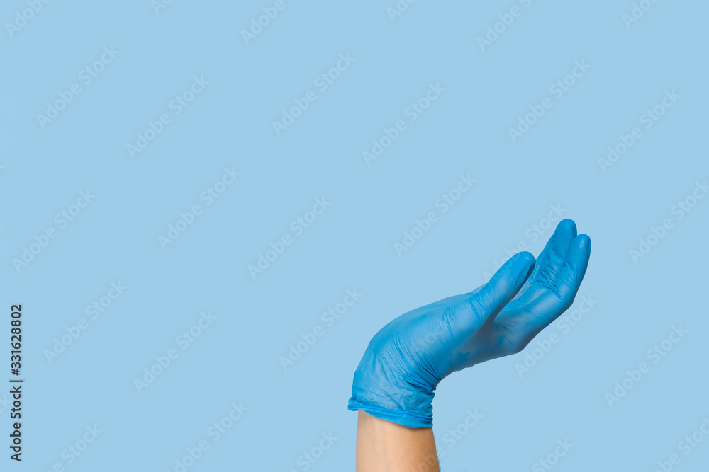 Doctor's hand in a blue medical glove holds an object on a blue background. infection control. mocap, you can insert your product for advertising Doctor's hand in a blue medical glove holds an object on a blue background. infection control. mocap, you can insert your product for advertising