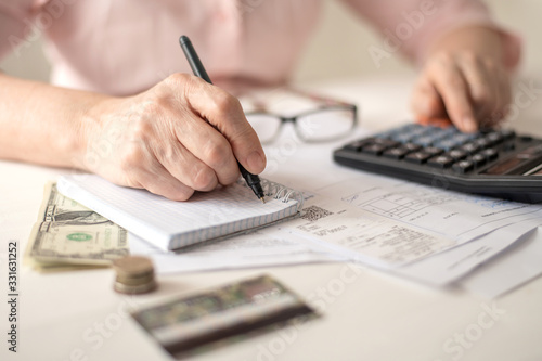 Pension calculation concept, old hands counting finances on a home calculator , close- up