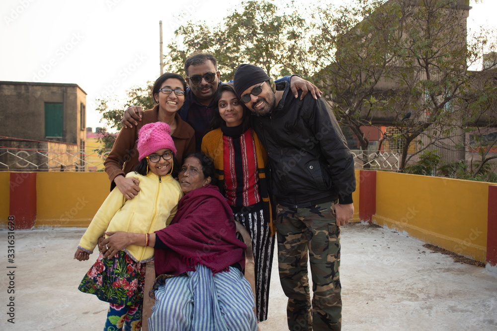 A cheerful Indian Bengali family in winter garments enjoying in a sunny winter afternoon on a rooftop. Indian lifestyle.