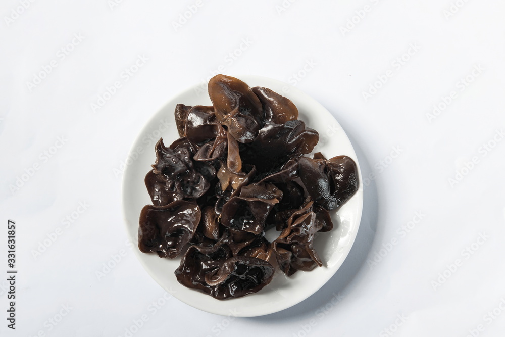 Dried agaric is isolated in a wooden bowl on a white background. Tile (top) driven fengus Dried agaric is isolated in a wooden bowl on a white background. Tile (top) driven fengus