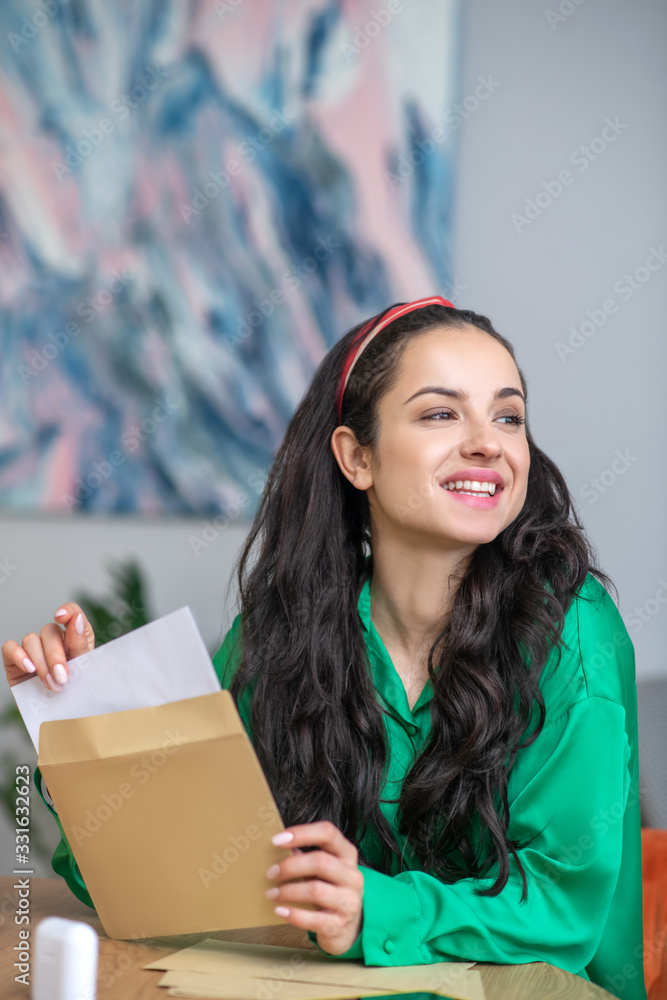 Obraz premium Satisfied young woman with an envelope in her hands.