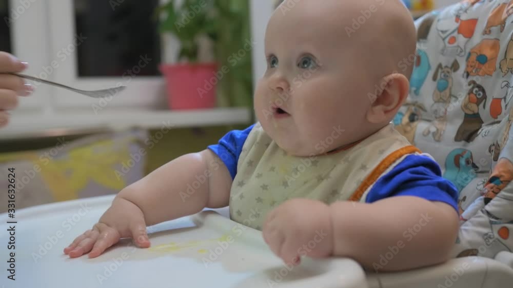 Mother feeding little baby with porridge at home kitchen. Mother feeding little baby with porridge at home kitchen.