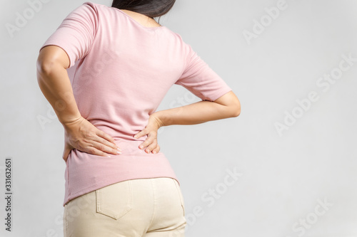 Young woman feeling pain in her back on white background. Healthcare and medical concept.