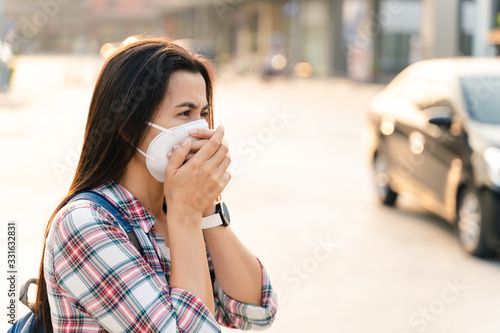 Asian woman wearing N95 mask to protect pollution PM2.5 and virus. COVID-19 Coronavirus and Air pollution pm2.5 concept. © Suriyawut