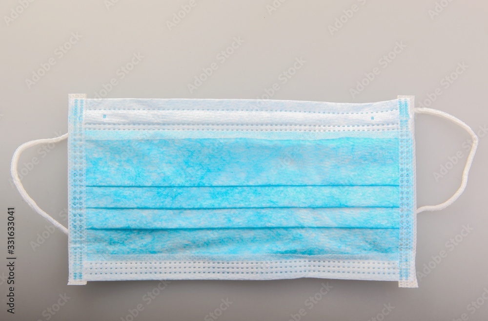 Fototapeta premium Typical three-layer protective surgical mask. The edge with double stitches is designed to cover the nose, and a metal wire is concealed within so the mask can be fitted securely to the nasal bridge.