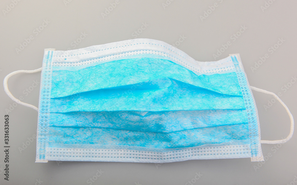 Fototapeta premium Typical three-layer protective surgical mask. The edge with double stitches is designed to cover the nose, and a metal wire is concealed within so the mask can be fitted securely to the nasal bridge.