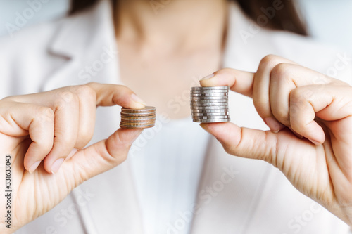 Hands compare two piles of coins of different sizes.