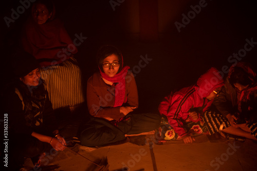 A cheerful Indian Bengali brunette family in winter wear enjoying bonfire on rooftop in the evening. Indian lifestyle and winter.