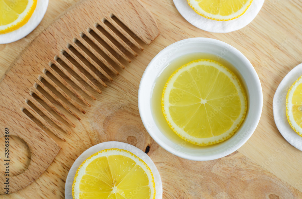 Lemon juice, lemon slices and wooden hair comb. Ingredients for preparing homemade hair mask or face toner. Natural beauty treatment recipe and zero waste concept. Top view, copy space. Lemon juice, lemon slices and wooden hair comb. Ingredients for preparing homemade hair mask or face toner. Natural beauty treatment recipe and zero waste concept. Top view, copy space.