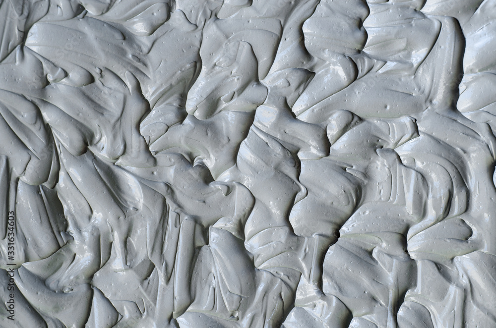 Obraz premium Gray bentonite facial clay (mask, face cream, body wrap) texture close up, selective focus. Abstract background with brush strokes.