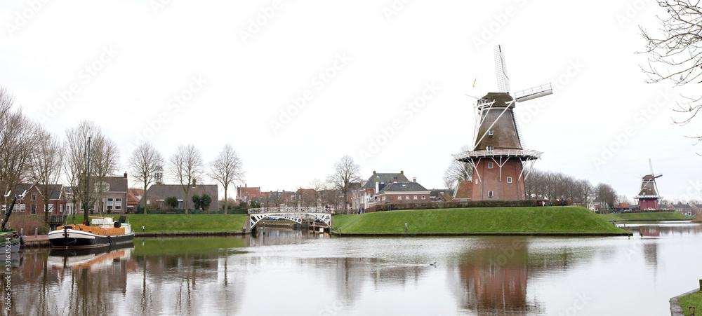Dokkum, the Netherlands on December 26, 2019: Canal and windmill on fortifications of fortified town of Dokkum, Friesland, Netherlands