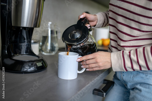 Woman hands pouring coffee into white cup