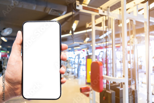 Close-up of female use Hand holding smartphone blurred images touch of Abstract blur of defocused sport gym interior and fitness health club with sports exercise equipment Gym blur background.