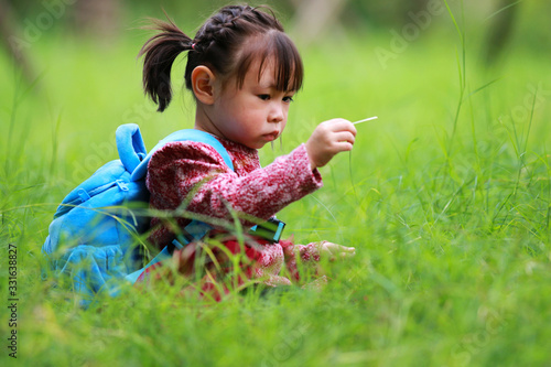 A little girl sitting on the grass playing alone photo