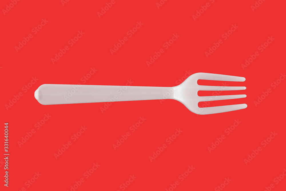 One plastic white fork on a red background. isolate. Top view. One plastic white fork on a red background. isolate. Top view.