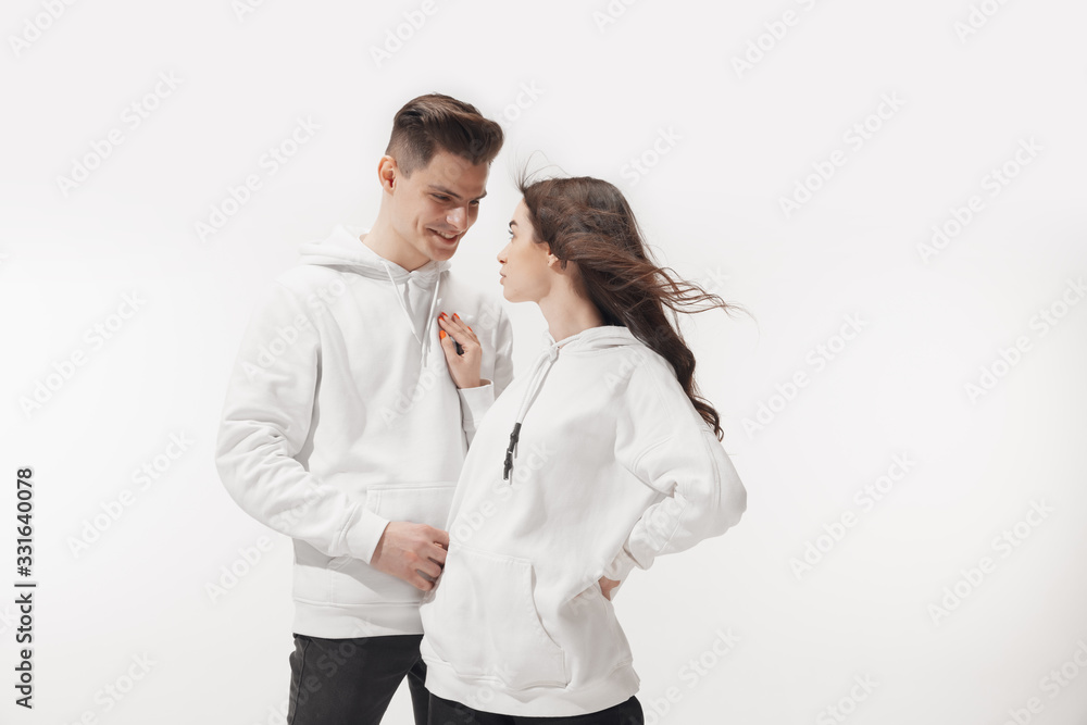 In white. Trendy fashionable couple isolated on white studio background. Caucasian woman and man posing in basic minimal unisex clothes. Concept of relations, fashion, beauty, love. Inclusive. In white. Trendy fashionable couple isolated on white studio background. Caucasian woman and man posing in basic minimal unisex clothes. Concept of relations, fashion, beauty, love. Inclusive.