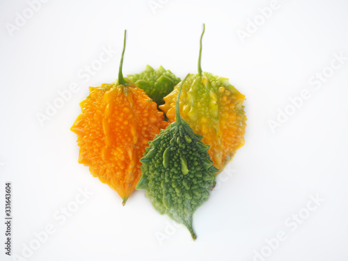 ripe and raw bitter gourd, balsam apple or bitter cucumber and carilla fruit with red  isolated on white background use as ingredient in cosmetic product and is a medicinal herb, close up shot photo. photo