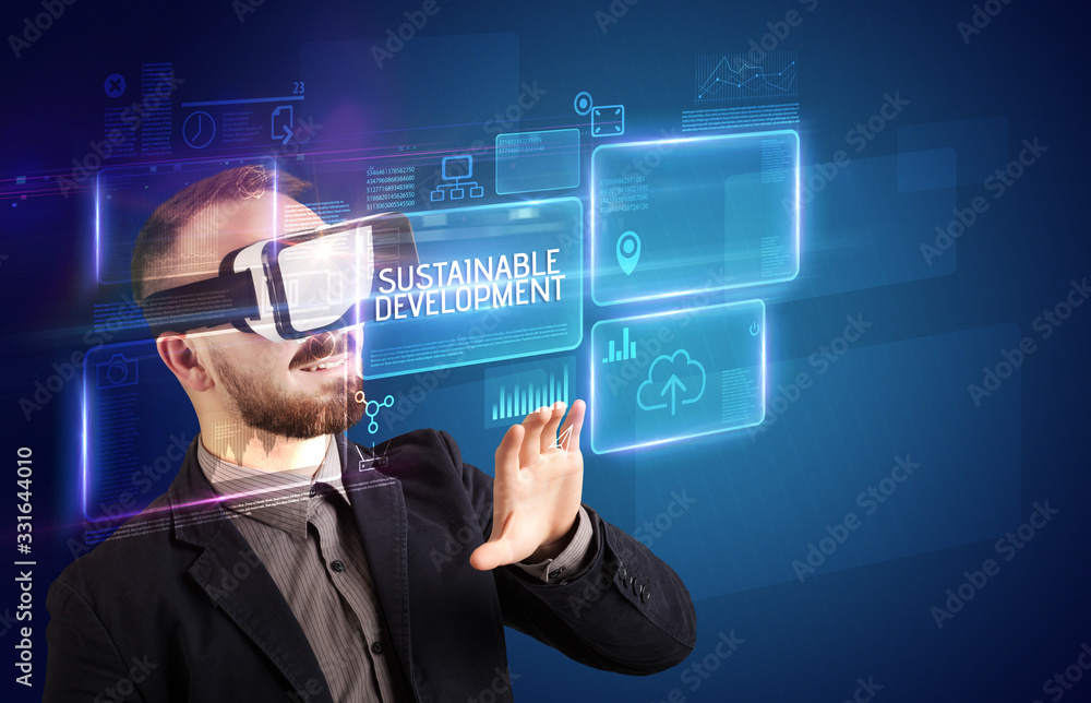 Businessman looking through Virtual Reality glasses with SUSTAINABLE DEVELOPMENT inscription, new technology concept Businessman looking through Virtual Reality glasses with SUSTAINABLE DEVELOPMENT inscription, new technology concept