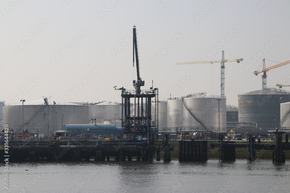 Jetty at pier and storage tanks at Shell Refinery in Pernis with Crude or fuel in the port of Rotterdam Jetty at pier and storage tanks at Shell Refinery in Pernis with Crude or fuel in the port of Rotterdam