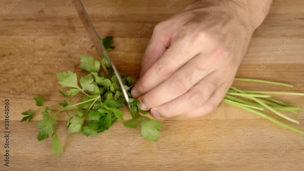 Cutting parsley on a cutting board viewed from above. Cutting parsley on a cutting board viewed from above.