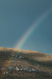 Birght rainbow rising over mountain on dark grey sky background