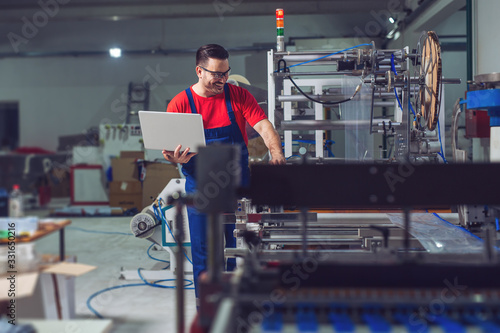 Industrial engineer with laptop in a industrial manufacture factory working.