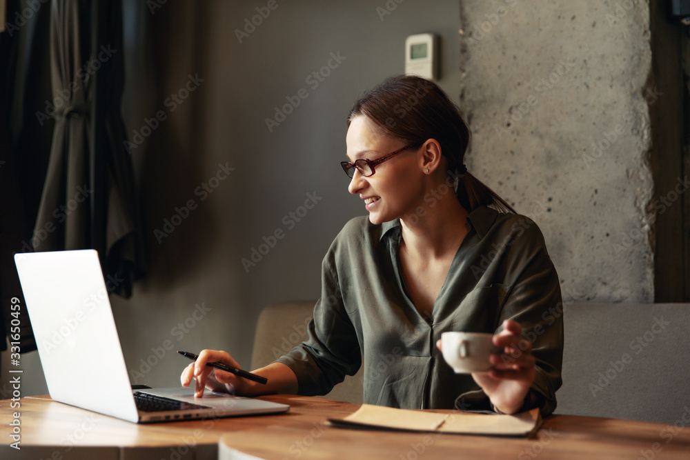 Focused business woman in stylish glasses sit on cafe working on laptop, concentrated serious female working with computer Focused business woman in stylish glasses sit on cafe working on laptop, concentrated serious female working with computer