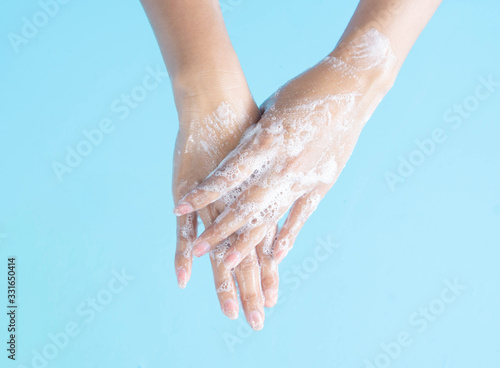 Cuadro en lienzo Closeup woman's hand washing with soap on blue background, health care concept