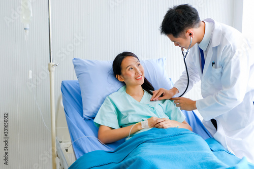 Close-up of Young male Asian doctor physician listening to action patient lie in bed heartbeat or breathing patients in the hospital/ Healthcare and medically concept.