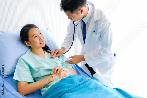 Close-up of Young male Asian doctor physician listening to action patient lie in bed  heartbeat or breathing patients in the hospital  Healthcare and medically concept.