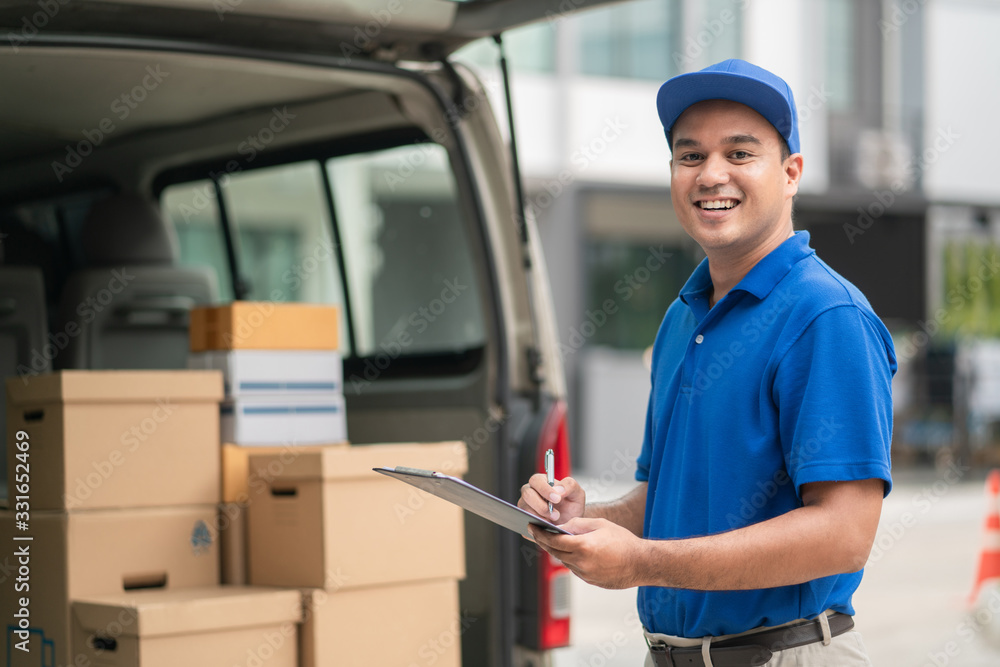 Young asian delivery in blue uniforms holding a clipboard. Messenger and delivery parcel cardboard concept. Young asian delivery in blue uniforms holding a clipboard. Messenger and delivery parcel cardboard concept.