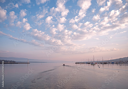 Fishermen leave to collect catches from pots. Sunrise over lake Geneva as the crew and their small boat head out from shore to check their morning catch.