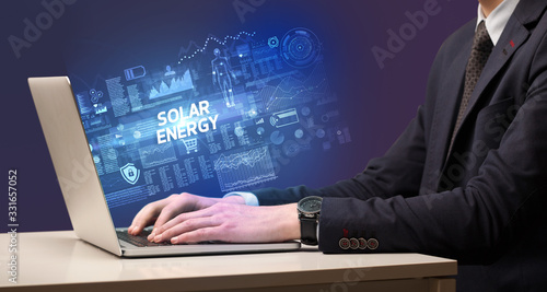 Businessman working on laptop with SOLAR ENERGY inscription, cyber technology concept