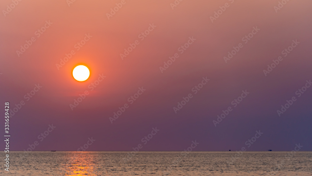 Amazing pink to purple sunset with orange sun over a tropical ocean