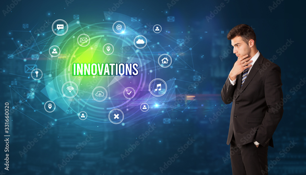 Businessman thinking in front of technology related icons and INNOVATIONS inscription, modern technology concept Businessman thinking in front of technology related icons and INNOVATIONS inscription, modern technology concept