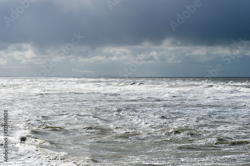 The Hague  South-Holland Netherlands - 200226  Wild sea with waves on a stormy day. Industrial area at the horizon