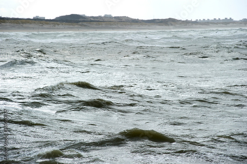 The Hague, South-Holland/Netherlands - 200226: Wild sea with waves on a stormy day with dunes and houses on the background © Sjoerd