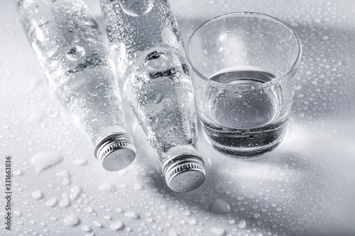 Glass water bottles and glass of water on white background photo