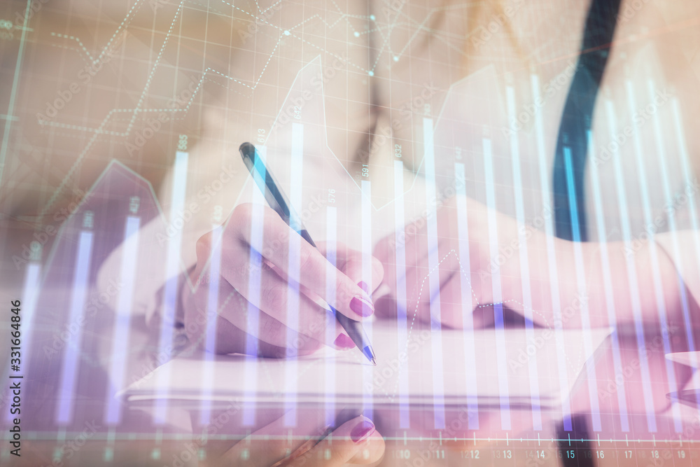 Double exposure of hands making notes with forex chart huds. Stock market concept.