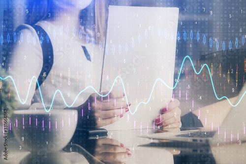 Double exposure of hands making notes with forex chart huds. Stock market concept.