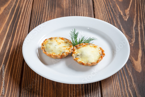 Plate of julienne with cheese and mushrooms on a wooden table photo