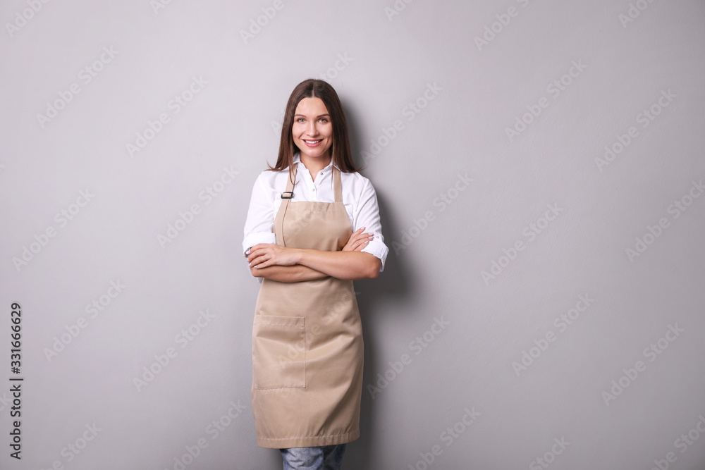 Young woman in an apron on a gray background. Young woman in an apron on a gray background.