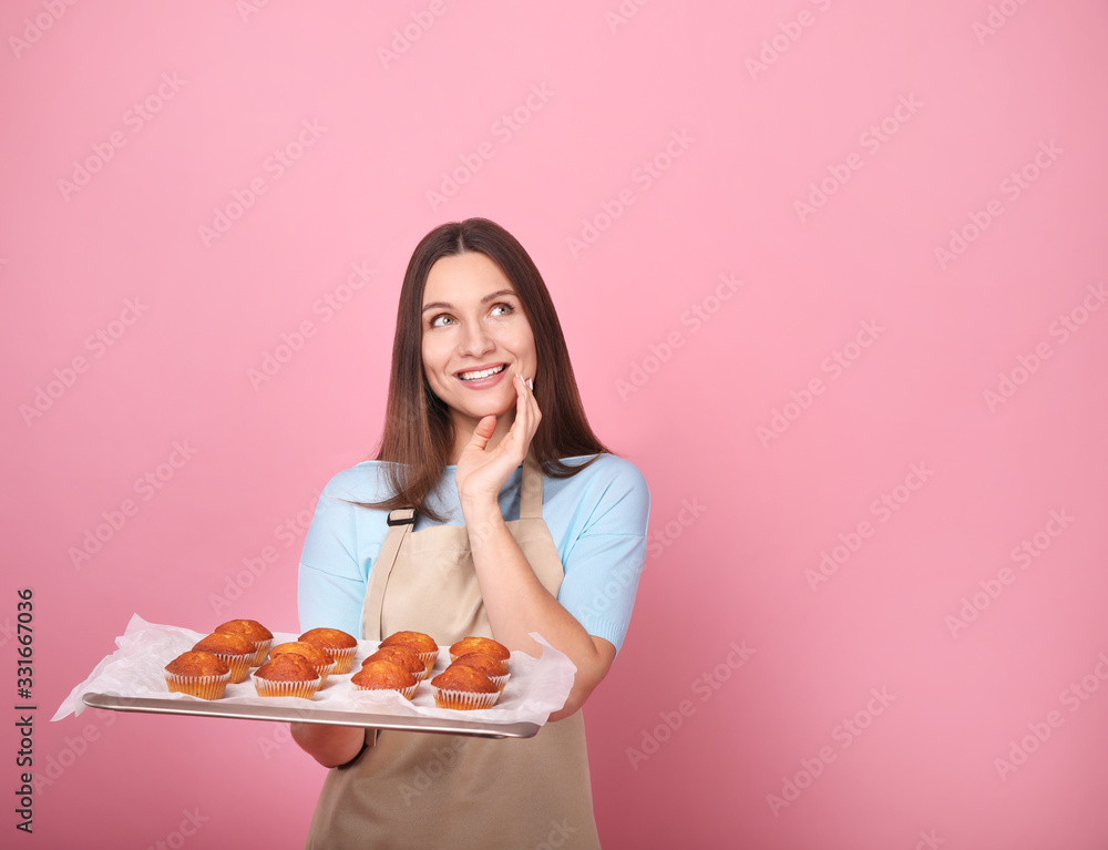 Young woman in apron with cupcakes on a yellow background Young woman in apron with cupcakes on a yellow background