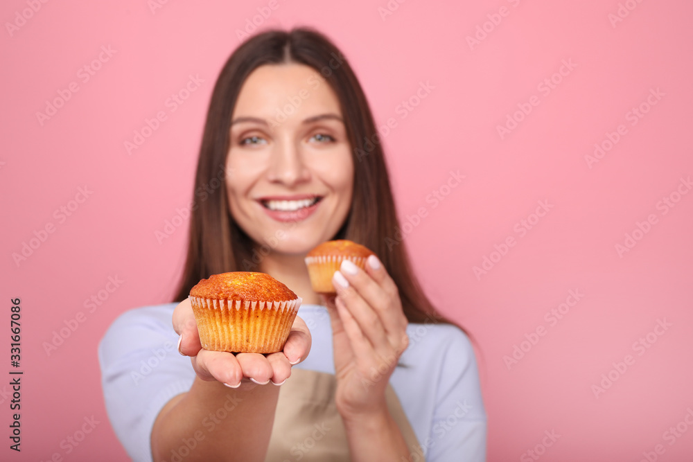 Young woman in apron with cupcakes on a yellow background Young woman in apron with cupcakes on a yellow background