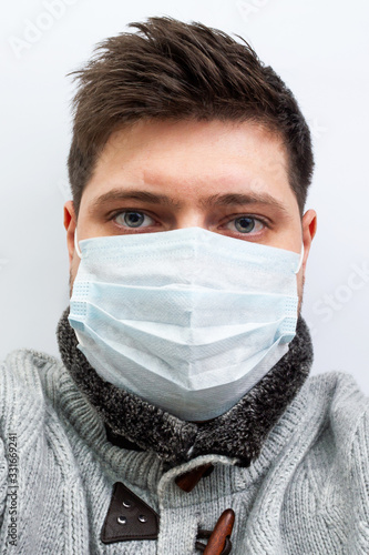 young guy caucasian in a medical mask in a sweater with bags under the eyes poor view. coronavirus covid 2019, quarantine