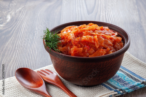 Braised cabbage with tomatoes on an old wooden background in rustic style