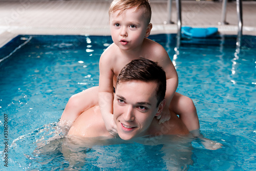 handsome swim coach holding cute toddler kid on shoulders in swimming pool © LIGHTFIELD STUDIOS
